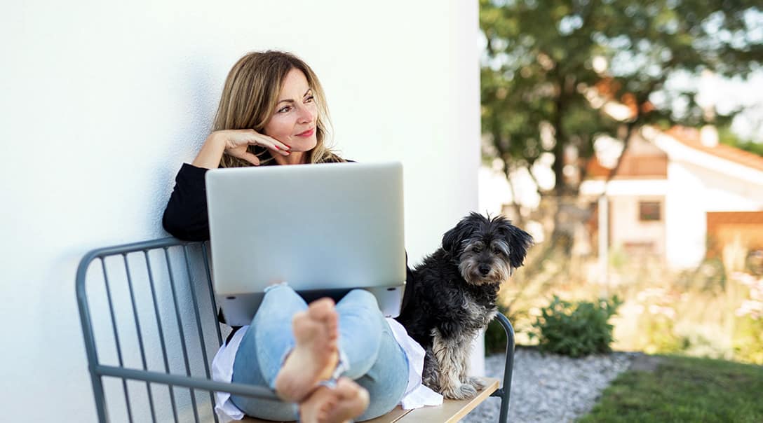 Woman sitting outside with her dog and laptop