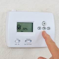 Person changing the temperature on a thermostat