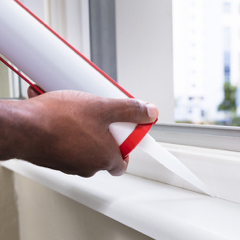 Person caulkig a window seal