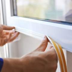 Person installing weather stripping on the bottom of a window